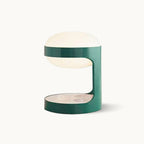 Clérachic table lamp on a plain white backdrop, a green metal cylinder cut open at the middle with a pale dome shade on top.