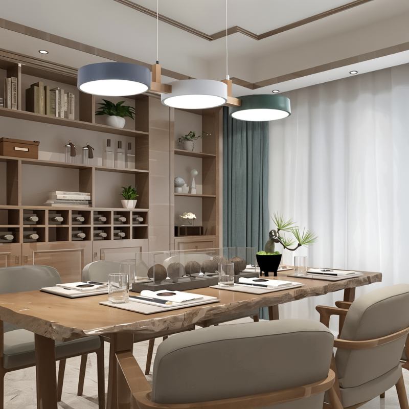 A Clérachic three-drum pendant lights a wood-panelled dining room, hung above a live-edge table and bookshelves.