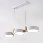 Clérachic's three-light pendant in matching white drum shades hangs from a slim wood crossbar and ceiling plate.