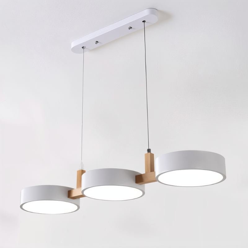 Clérachic's three-light pendant in matching white drum shades hangs from a slim wood crossbar and ceiling plate.