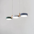 A Clérachic three-drum pendant in green, white and grey shades is shown lit against a soft grey studio backdrop.