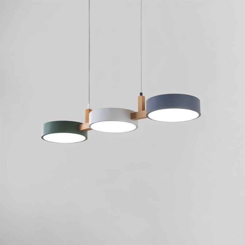 A Clérachic three-drum pendant in green, white and grey shades is shown lit against a soft grey studio backdrop.