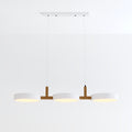 Clérachic's three-light pendant in all-white drum shades hangs lit from a rectangular white ceiling canopy.
