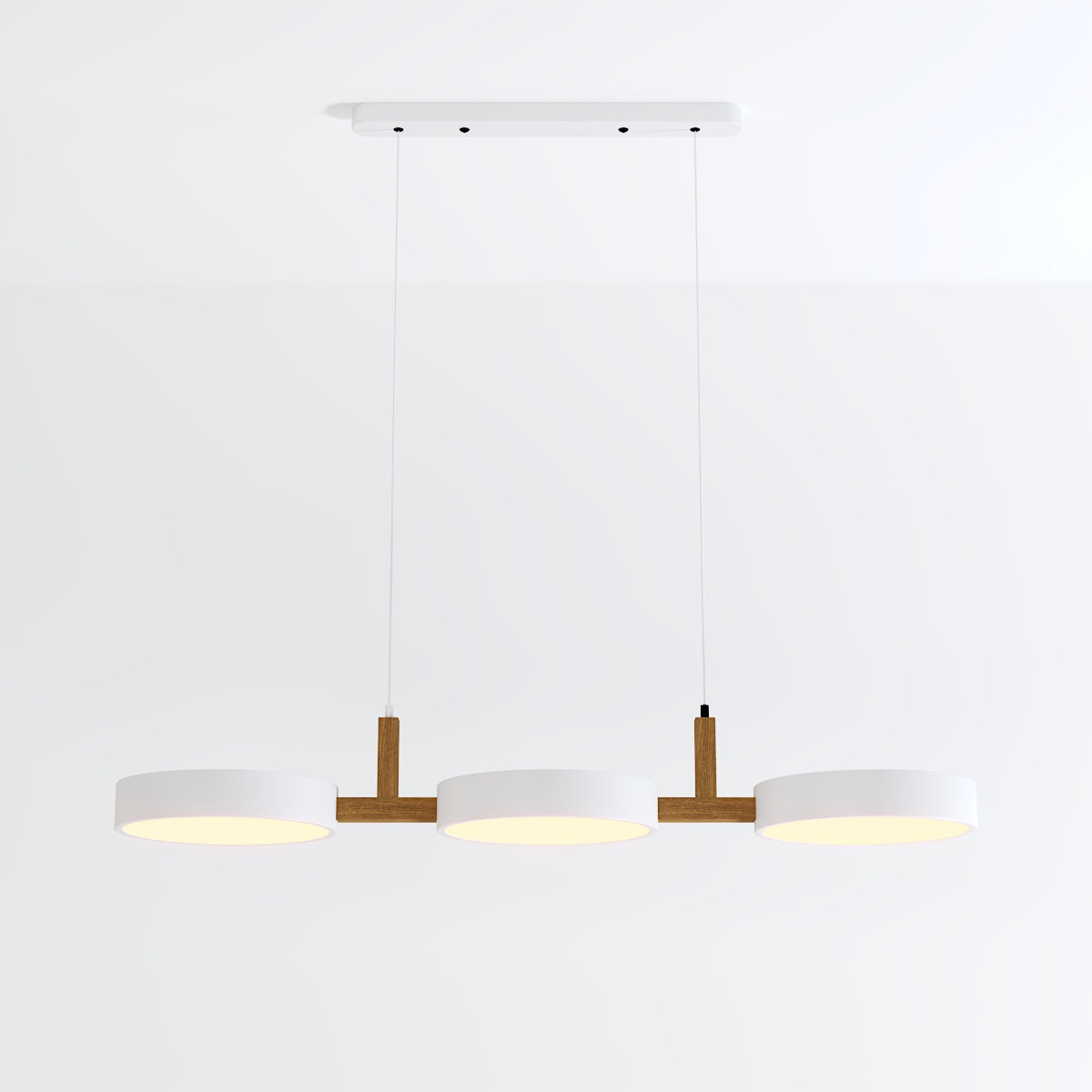 Clérachic's three-light pendant in all-white drum shades hangs lit from a rectangular white ceiling canopy.