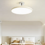 Clérachic cream LED disc ceiling light lit above a minimalist tufted white headboard with a curved wall nook.