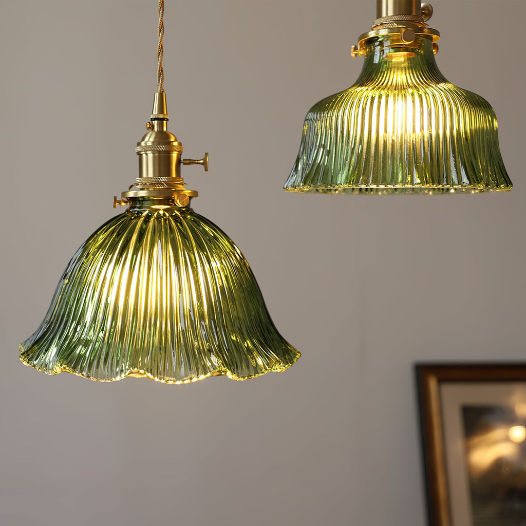 Warm light through the fluted green glass of this Clérachic pendant, with a second shade and a framed picture behind.