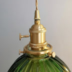 Close view of the brass socket, collar and fixing screws holding the dark-green ribbed shade on this Clérachic pendant.