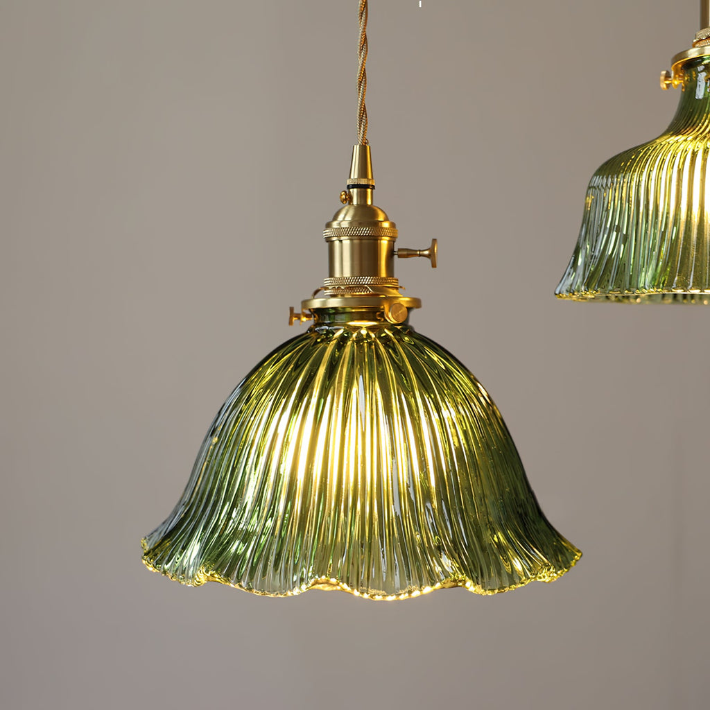 Lit green ribbed shade with a wavy rim and a brass switch holder, seen straight on against a grey wall, from Clérachic.