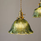 Lit green ribbed shade with a wavy rim and a brass switch holder, seen straight on against a grey wall, from Clérachic.