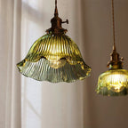 Looking up at the ribbed green glass of this Clérachic pendant, its frilled rim lit, with a second shade at the edge.