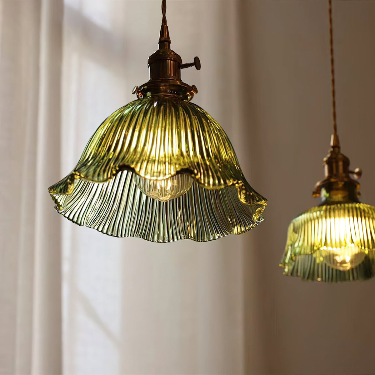 Looking up at the ribbed green glass of this Clérachic pendant, its frilled rim lit, with a second shade at the edge.