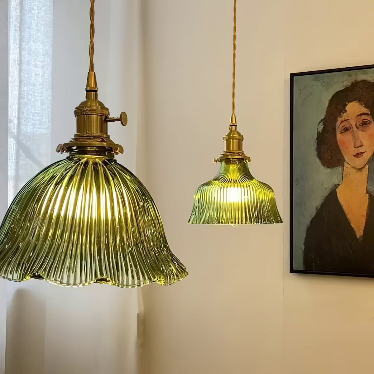Large and small green ribbed pendants hung together near a window and a framed portrait, both lamps from Clérachic.