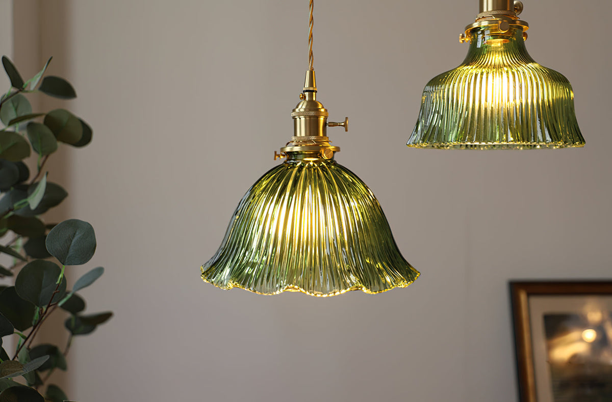 Lit green ribbed pendant with a second shade beside it, hung against a grey wall near a eucalyptus branch, from Clérachic.