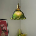 Green ribbed glass pendant with a scalloped rim lit in a corner above a red framed print, a lamp from Clérachic.