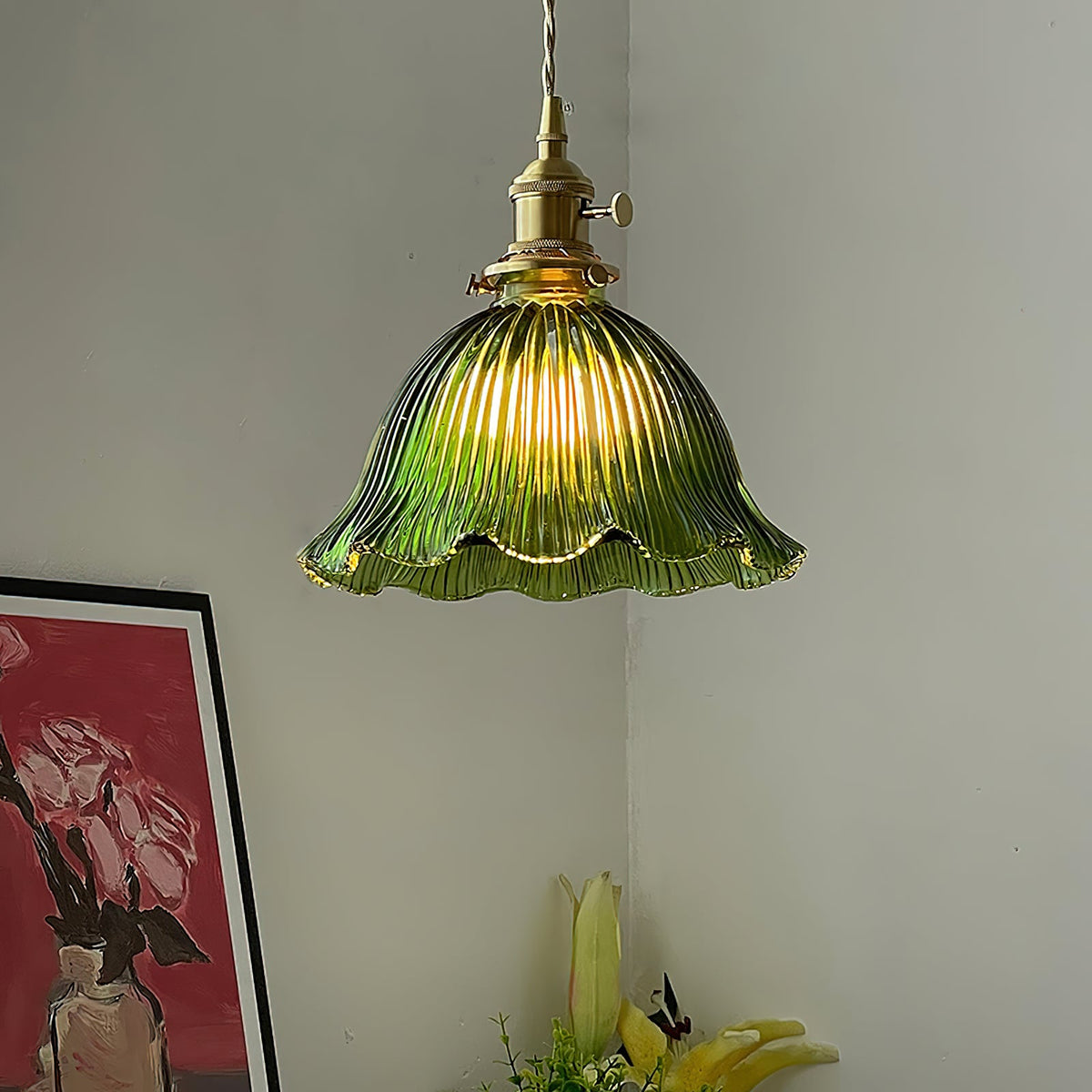 Green ribbed glass pendant with a scalloped rim lit in a corner above a red framed print, a lamp from Clérachic.