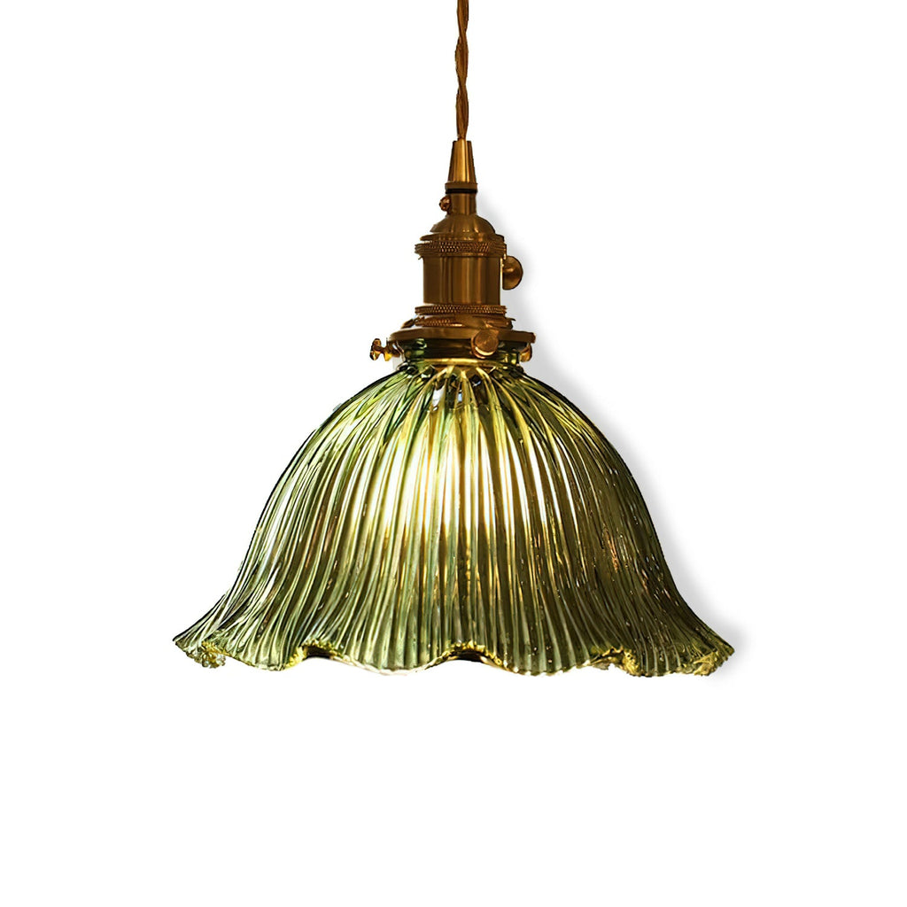 Green fluted glass shade with a wavy edge and brass socket, glowing warm on a white backdrop, from Clérachic.