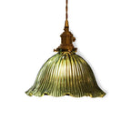 Green fluted glass shade with a wavy edge and brass socket, glowing warm on a white backdrop, from Clérachic.