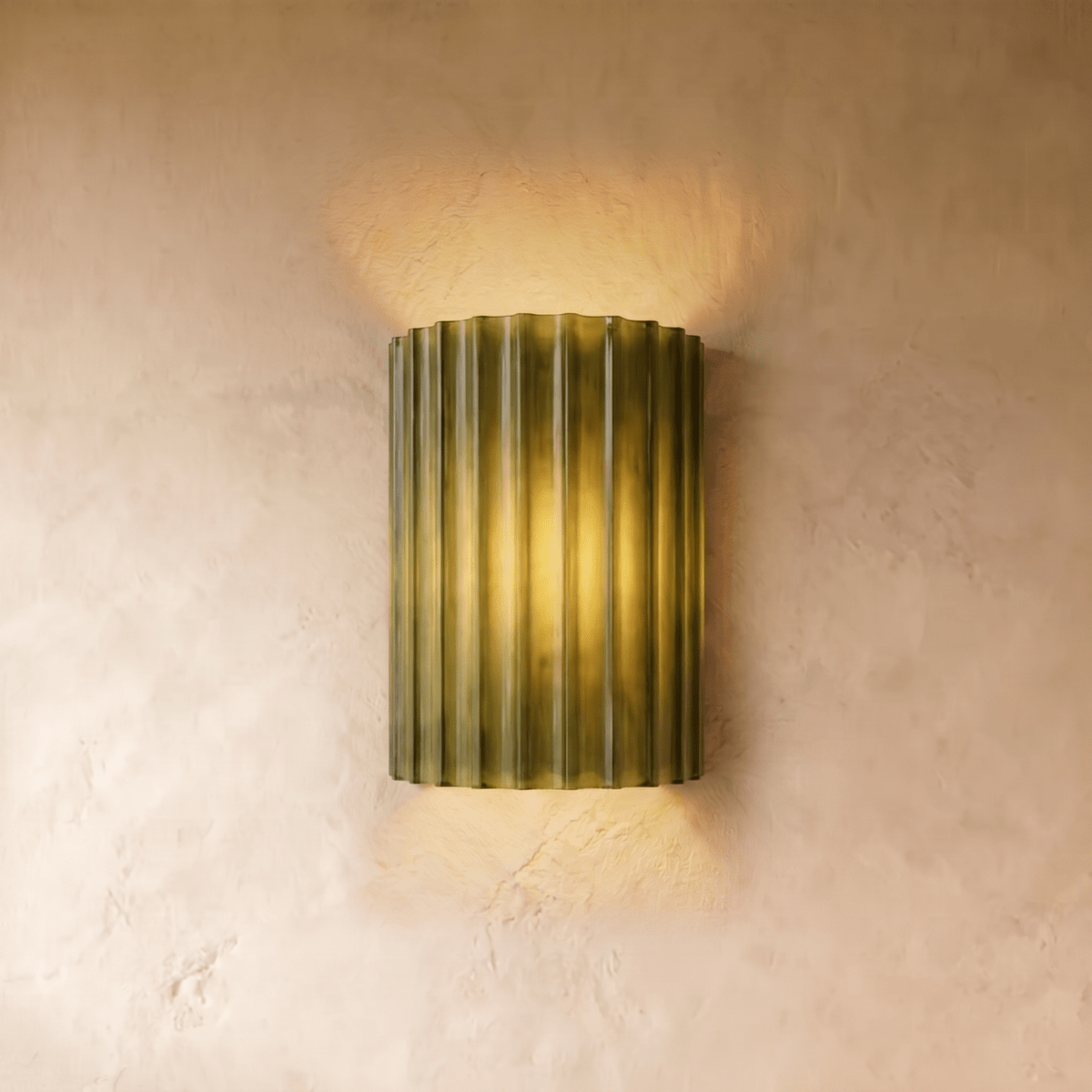 Clérachic wall lamp in olive green, fluted half-cylinder shade lit warm against a plain plaster wall.