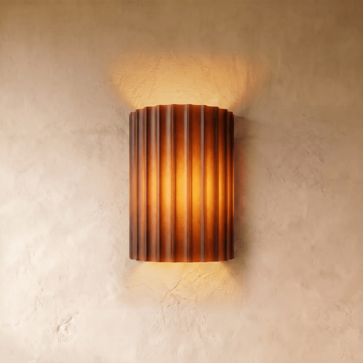 Clérachic wall lamp in burnt orange, fluted half-cylinder shade lit warm against a plaster wall.
