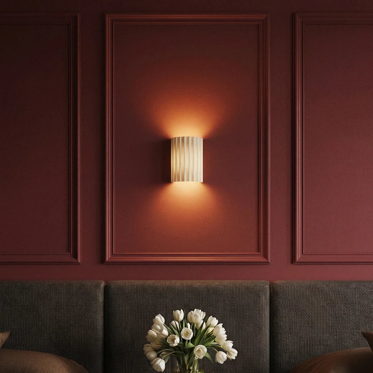 Clérachic wall lamp in white glowing warm within a burgundy wall panel above a tufted headboard and tulips.