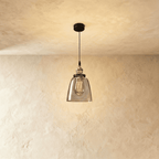 Clérachic pendant light in smoke-grey glass with a bell-shaped shade, hung against a warm plaster ceiling.