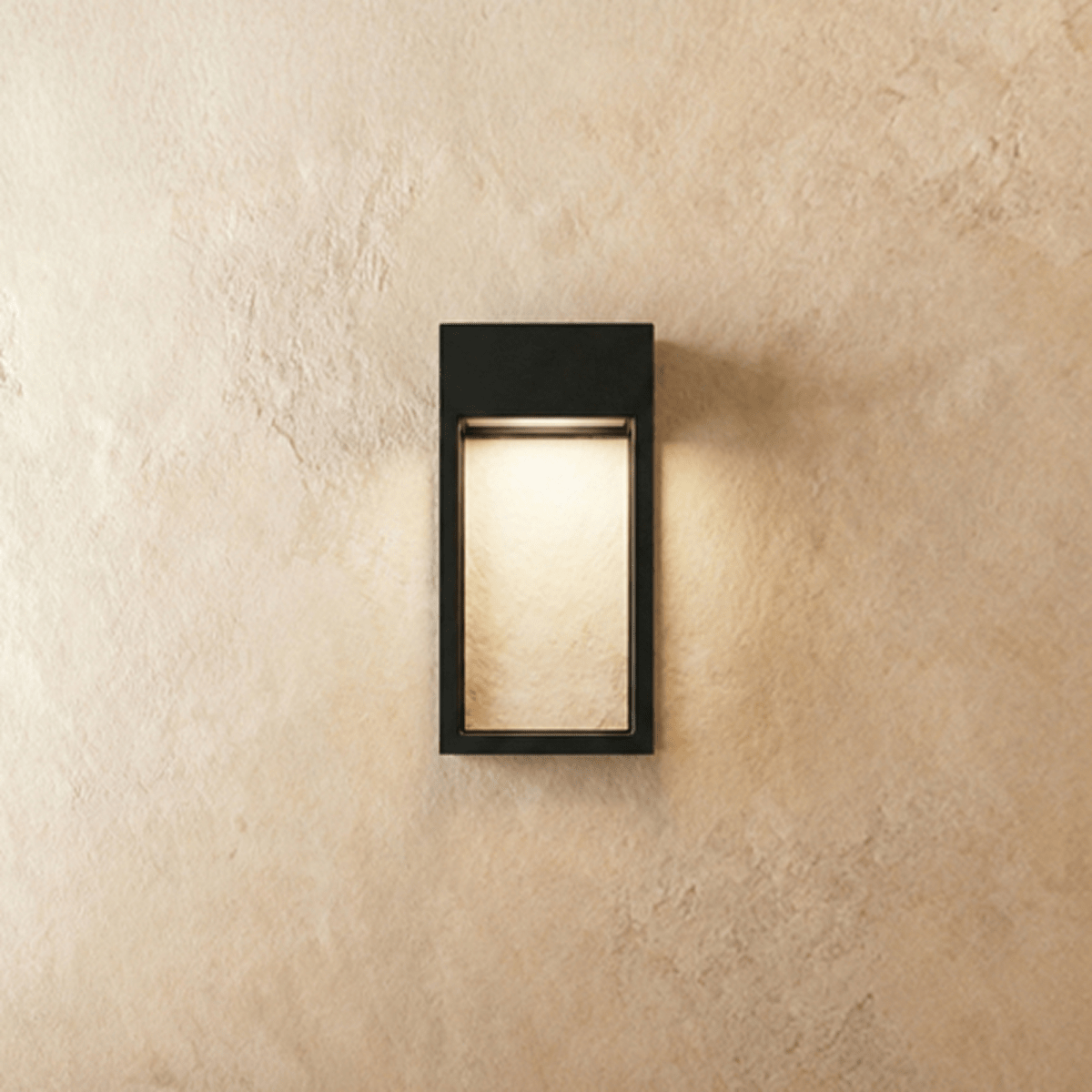 Clérachic grey steel wall sconce with an open rectangular frame, its LED strip glowing softly on a plaster wall.