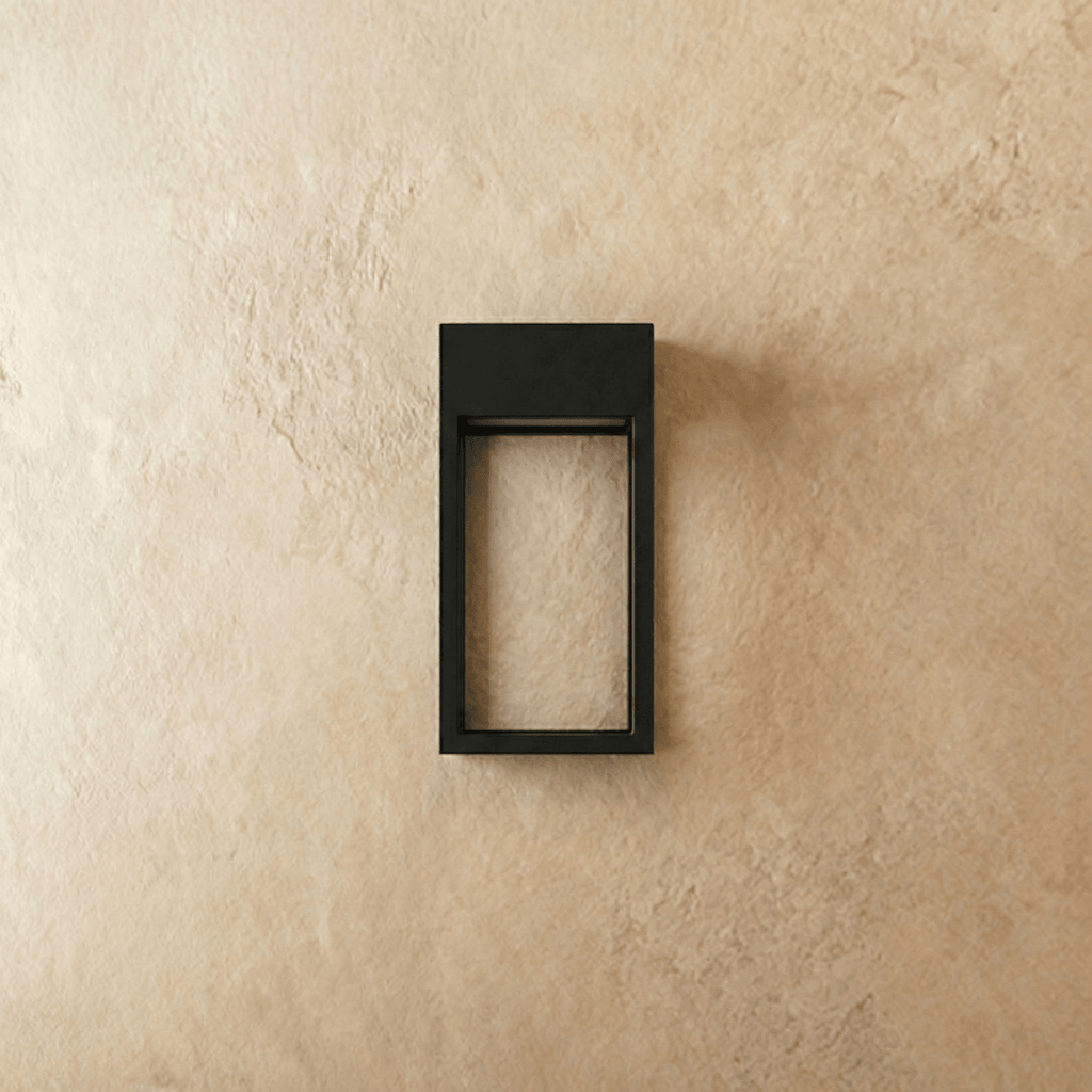 Clérachic grey steel wall sconce shown unlit, its open rectangular frame mounted flush on a plaster wall.