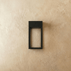 Clérachic grey steel wall sconce shown unlit, its open rectangular frame mounted flush on a plaster wall.