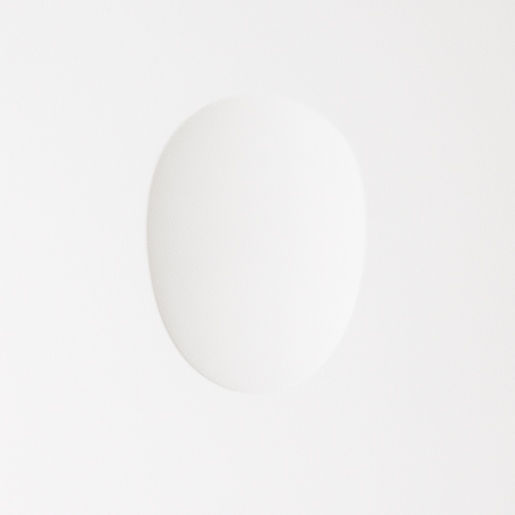 This Clérachic trimless wall sconce sits flush in white plaster, its oval light gently warming the surface.
