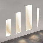 Four Clérachic trimless wall sconces of different heights glow along a gray hallway wall near the floor.