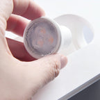 A hand fits the small warm-white LED module into a Clérachic trimless wall sconce before it is set into plaster.