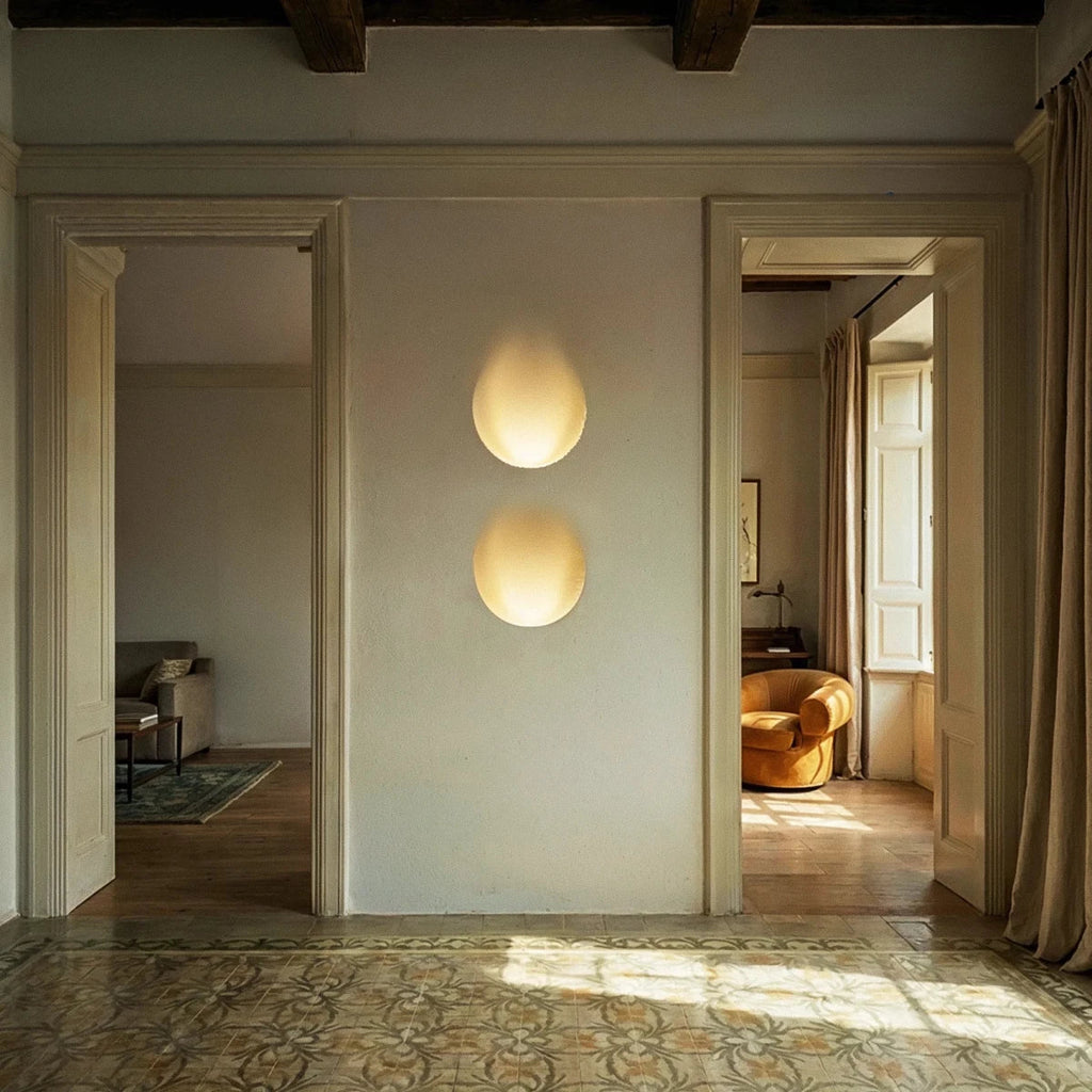 Two stacked Clérachic trimless wall sconces glow warmly in a hallway between two open doorways at sunset.