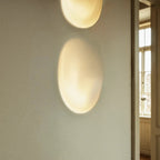This tight crop highlights the Clérachic sconce's warm glow stacked low on a plaster wall beside a window.