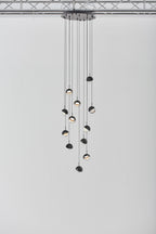 Clérachic pendant cluster with matt black caps hung from a round black ceiling plate against a pale grey wall.