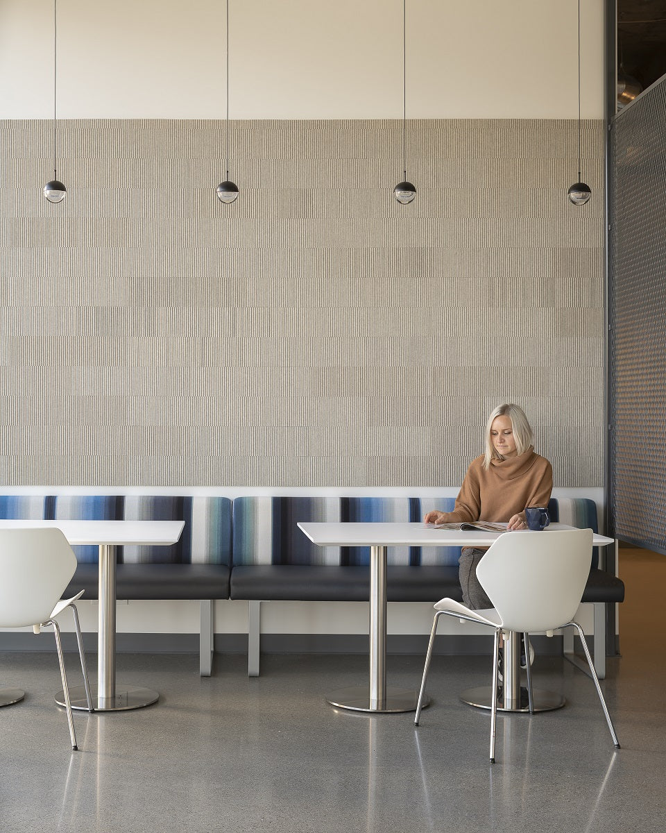 Row of four small Clérachic globe pendants along a wall, above a banquette where a woman sits at a white table.