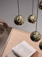 Looking down on gold-finish Clérachic globe pendants, with a wooden desk and an open book below.