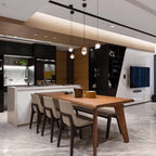 Three Clérachic globe pendants hung above a walnut dining table with grey chairs, in an open kitchen with a marble wall.