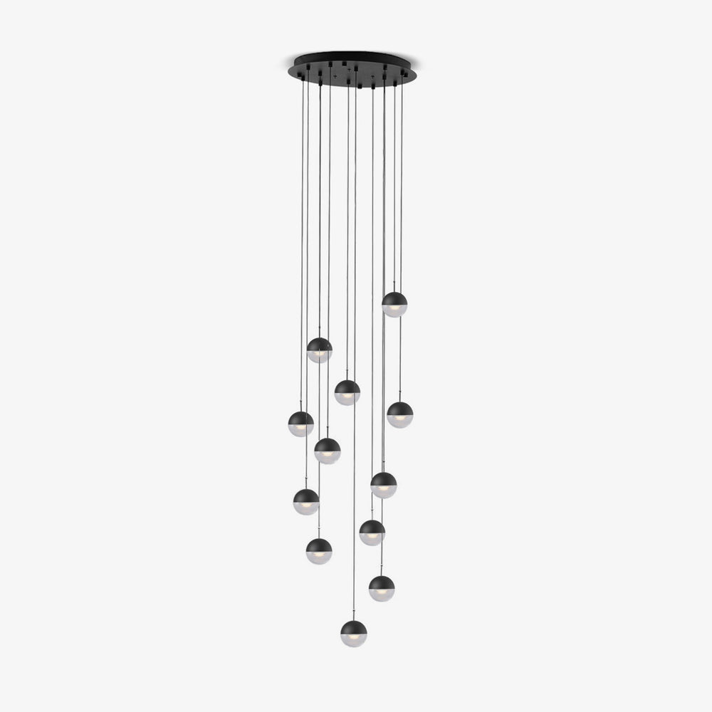 Clérachic pendant cluster with matt black caps and clear lower halves, hung at varied heights from a round black ceiling plate.