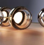 Close view of gold-finish Clérachic globe pendants glowing warmly, with the LED reflected in the glass.