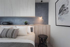 Single gold-finish Clérachic globe pendant on a short drop beside a bed, with a grey feature wall and a framed print.