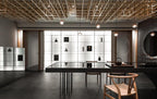 Small Clérachic globe pendants hung among a timber lattice ceiling above a dark table and wooden chairs.