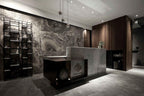 Clérachic globe pendants hung low over a stone reception counter in front of a marbled dark wall and black shelving.