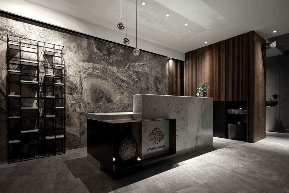 Clérachic globe pendants hung low over a stone reception counter in front of a marbled dark wall and black shelving.