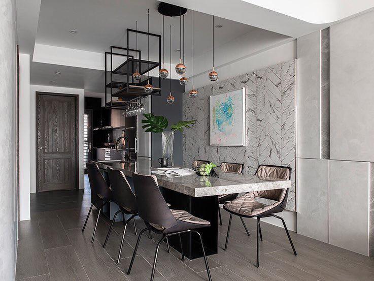 Small Clérachic globe pendants hung in a group over a marble-topped dining table, with leather chairs and a herringbone stone wall.