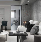 Clérachic globe pendants glowing softly beside a marble feature wall, with a grey sofa and a dark green armchair in the room.