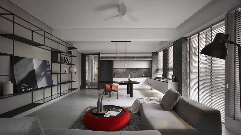 Wide open-plan room with a grey sofa and a red pouffe, with small Clérachic pendants just visible over the far dining table.