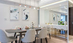 Clérachic globe pendants hung in a line over a dining table with grey chairs, beside a mirrored wall and a white sideboard.