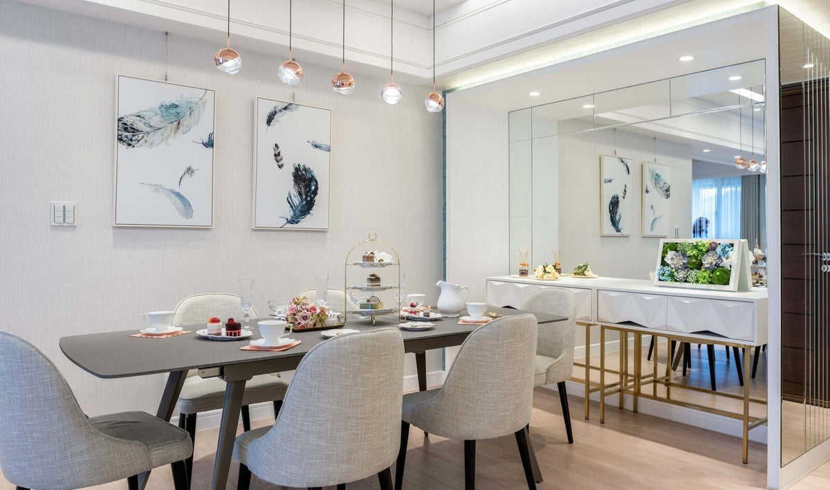 Clérachic globe pendants hung in a line over a dining table with grey chairs, beside a mirrored wall and a white sideboard.