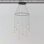 Clérachic ring chandelier with clear glass globes and gold-toned caps hung from a black ceiling plate under a ceiling truss.
