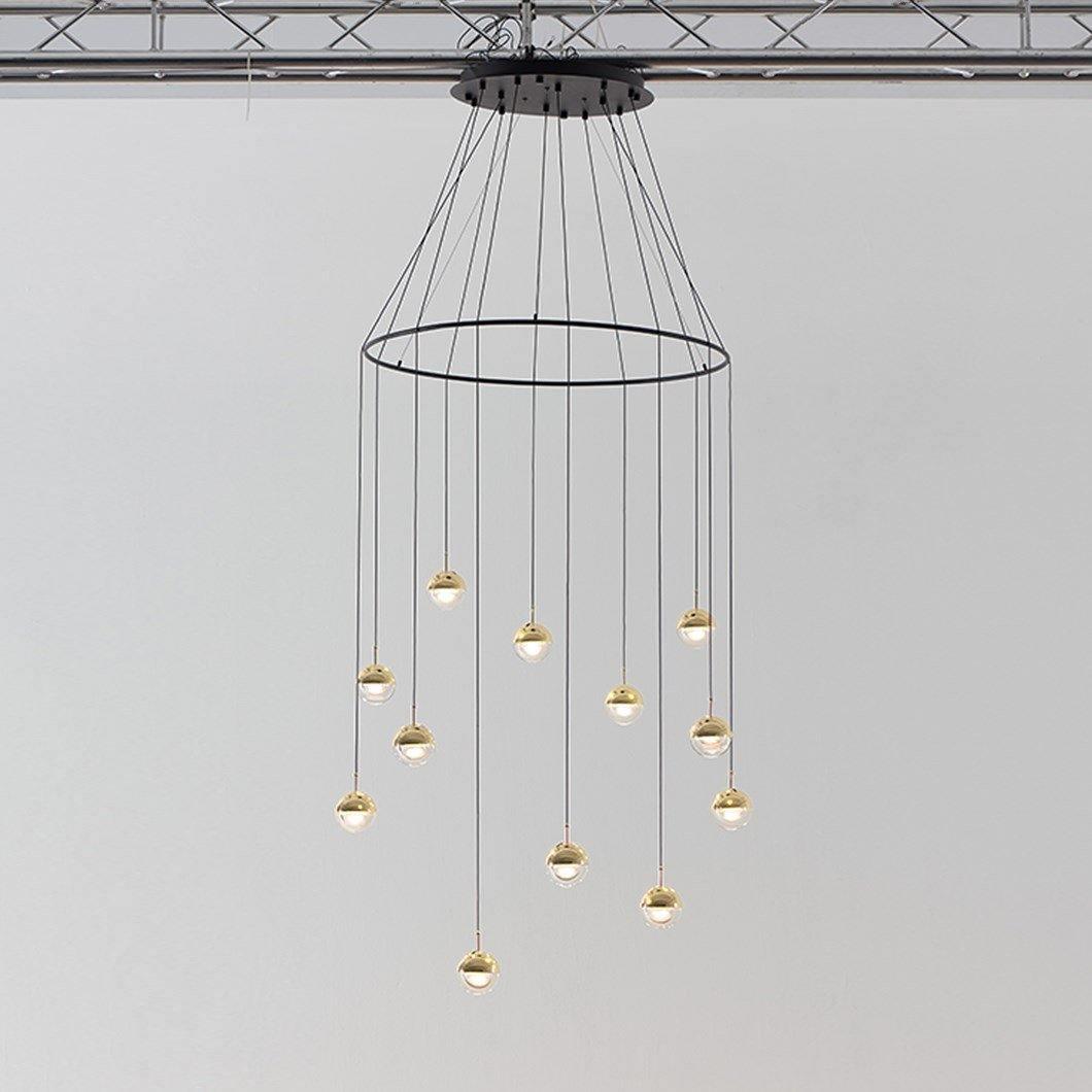 Clérachic ring chandelier with clear glass globes and gold-toned caps hung from a black ceiling plate under a ceiling truss.